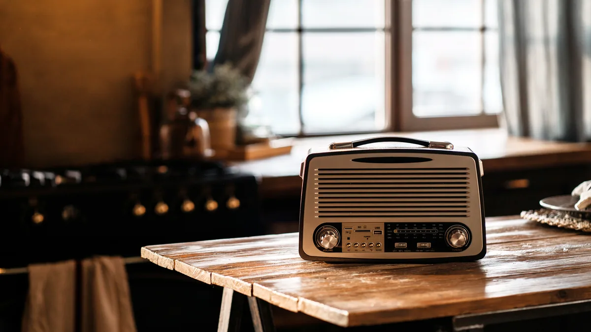 A vintage radio with its dial glowing on a wooden table.