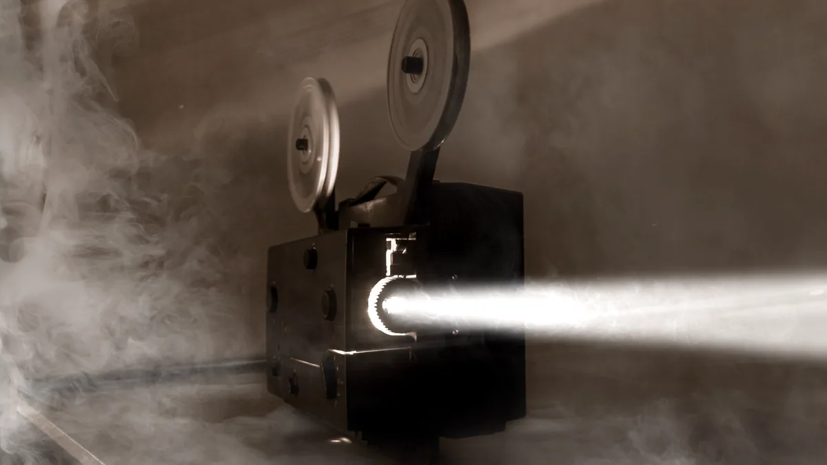 An old movie projector throwing a beam of light into a dark room.
