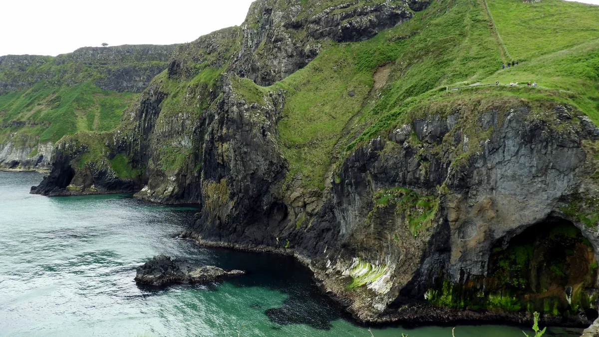 Steep green cliffs meeting the atlantic waves along the irish coast.