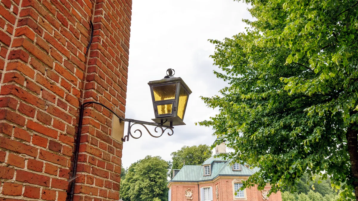 A narrow colonial brick street with an old iron lamppost at dusk.