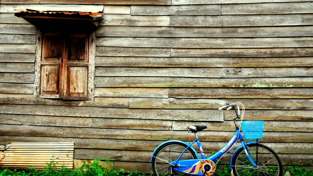 A child's bicycle leaning against the wall of an old farmhouse.